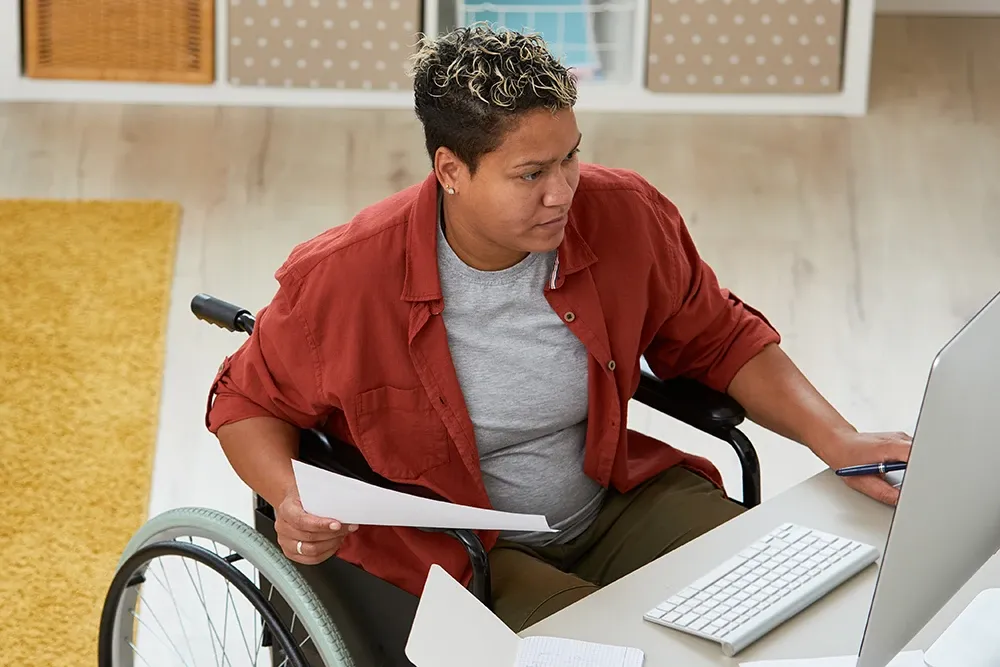 A woman in a wheelchair working on her computer.